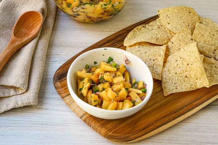 A small bowl with peach salsa and tortilla chips on the side.