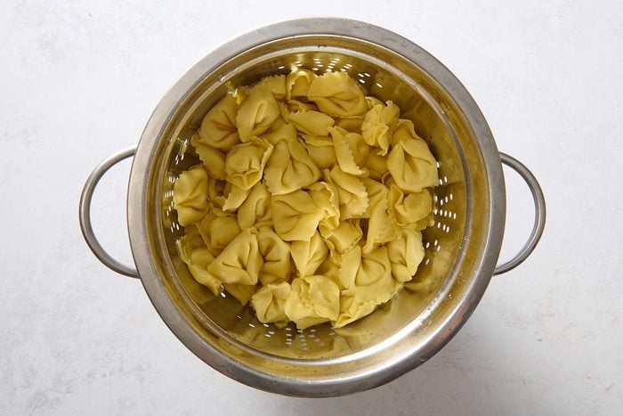 Cooked tortellini draining in a colander
