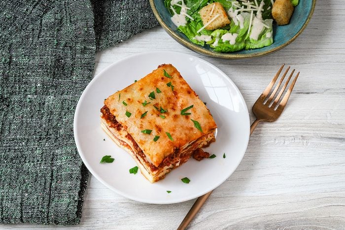Overhead photo of pizza lasagna and Caesar salad.
