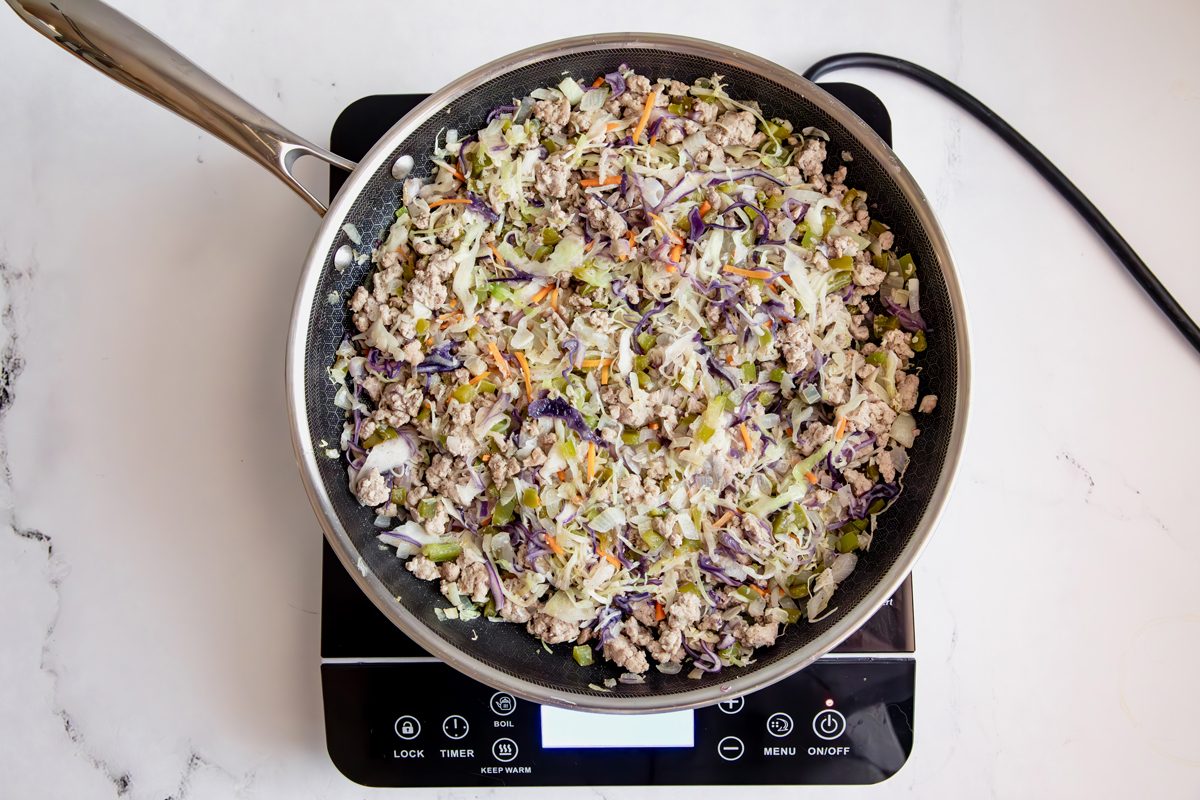Overhead shot for Taste of Home Sausage Egg Rolls, ingredients cooking on a HexClad over an induction cooktop.