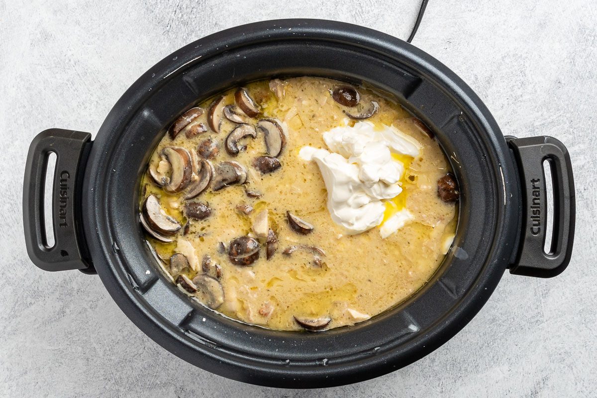adding the mushrooms and sour cream to the crockpot.