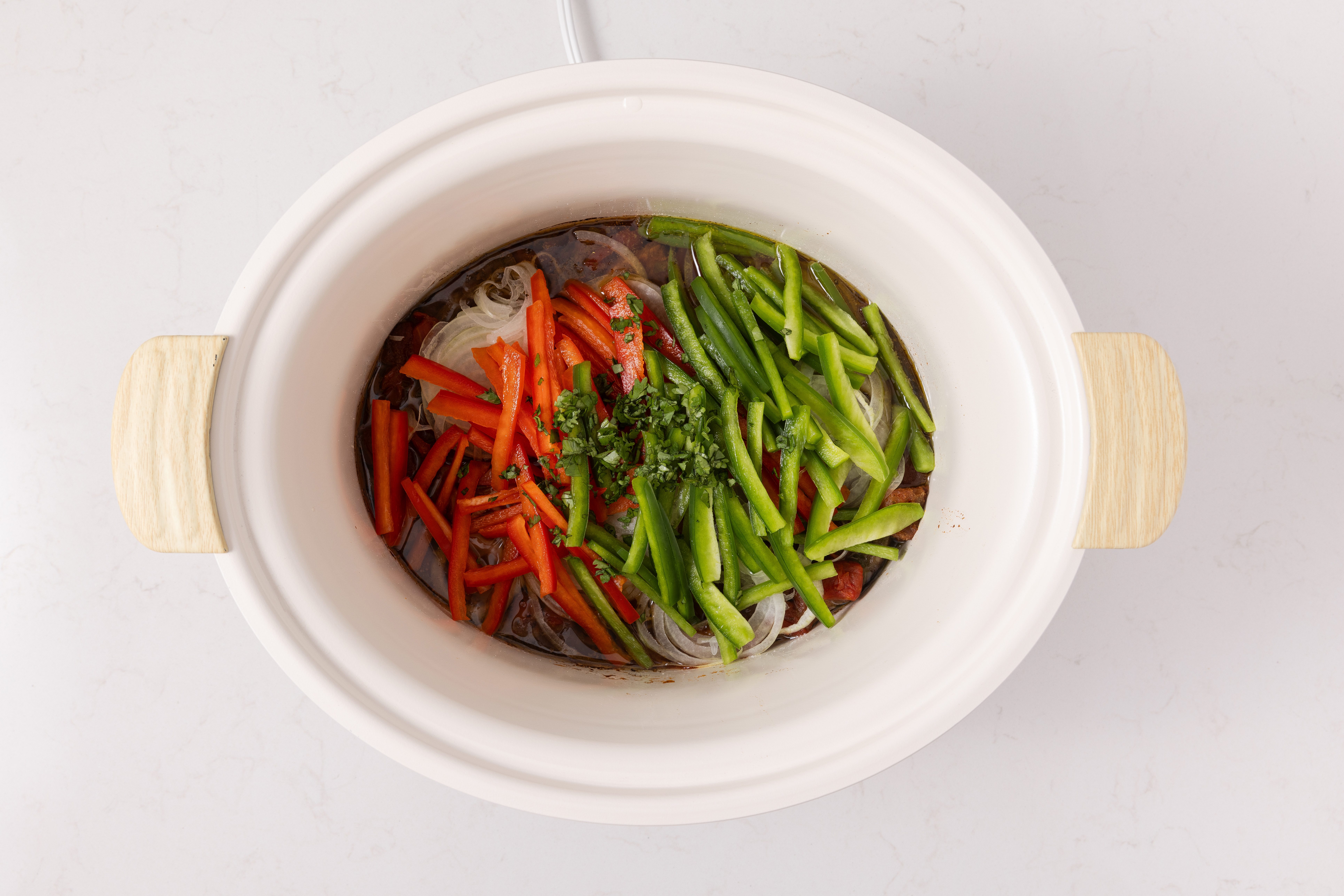Onions, sweet red pepper, green pepper and minced fresh cilantro added to the slow cooker.