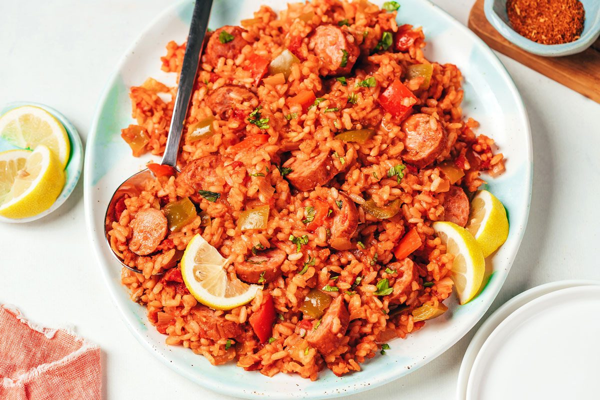 Spanish rice with sausage recipe by Taste of Home served on a large platter topped with chopped fresh parsley and lemon wedges