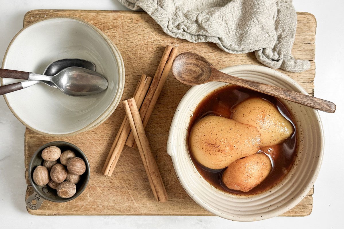 Taste of Home Spiced Pears in a ceramic bowl with wooden spoon on a wooden board