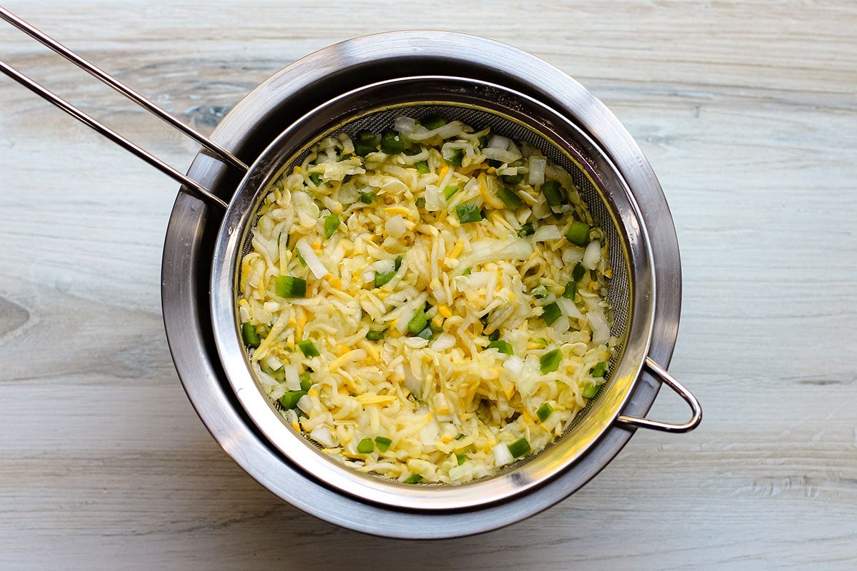 Straining the salted squash, bell pepper, and onion in preparation for squash relish.