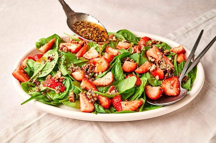 Dressing being drizzled with a metal spoon over the Strawberry Spinach Salad recipe by Taste of Home
