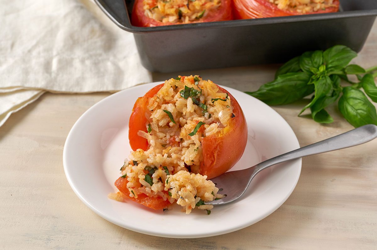 A close-up of the Stuffed Tomatoes, showcasing the crisp, golden top and the vibrant filling of rice and herbs, for the Stuffed Tomatoes with Rice recipe, by Taste of Home.
