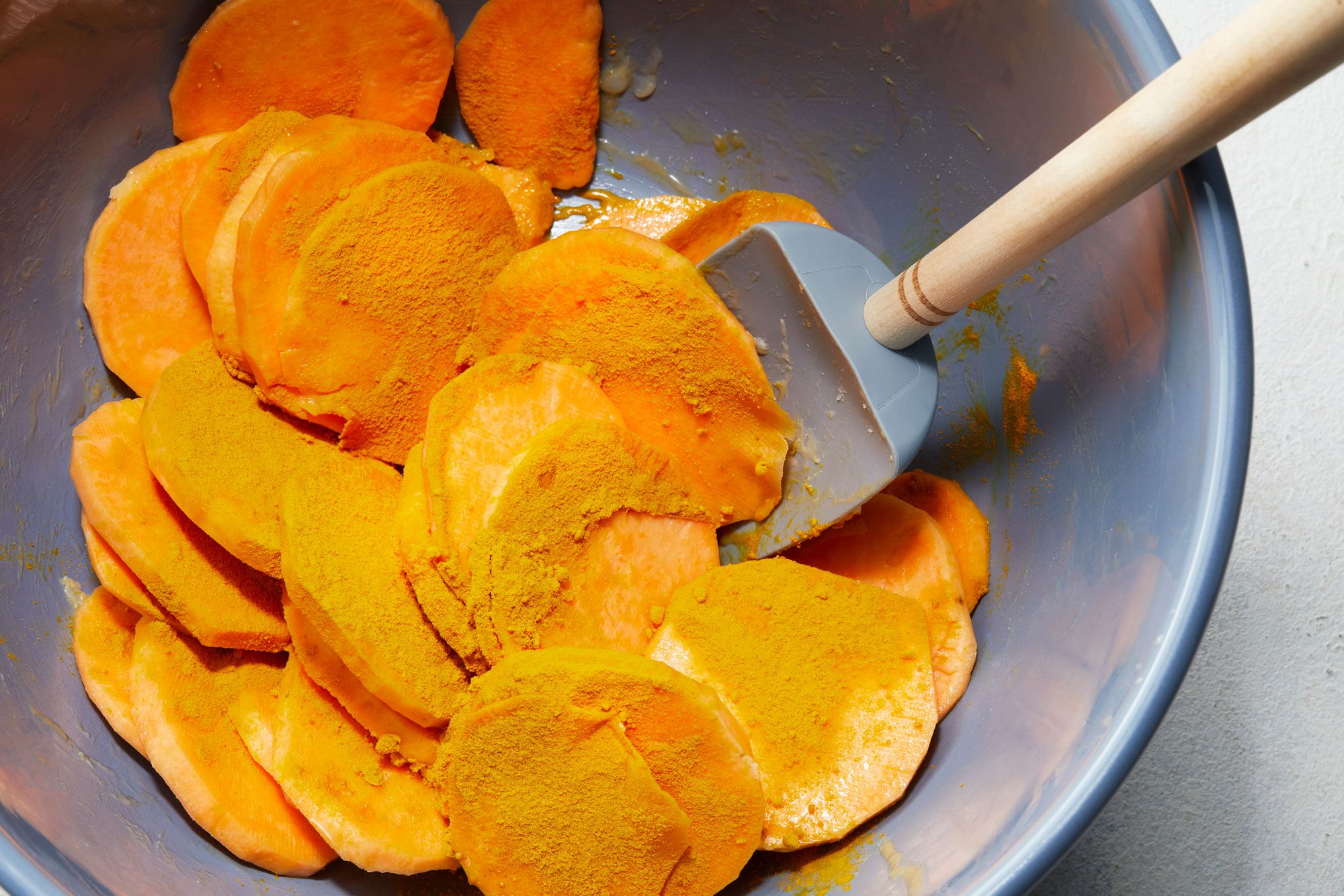 In a large bowl, toss sweet potato slices with melted coconut oil to coat