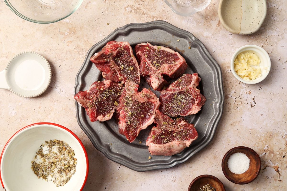 Process of making Taste of Home's Slow Cooker seasoned lamb chops on as silver plate on a beige marble surface.