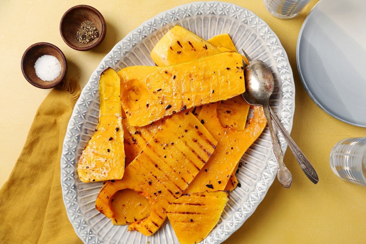 Close up of Taste of Home's Grilled Squash grilled butternut squash on a platter on a bright yellow surface.