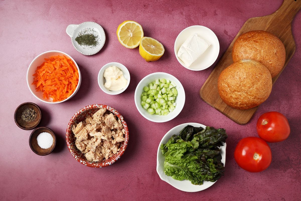 Ingredients for Taste of Home's salmon salad sandwich laid out in small bowls on a magenta surface.