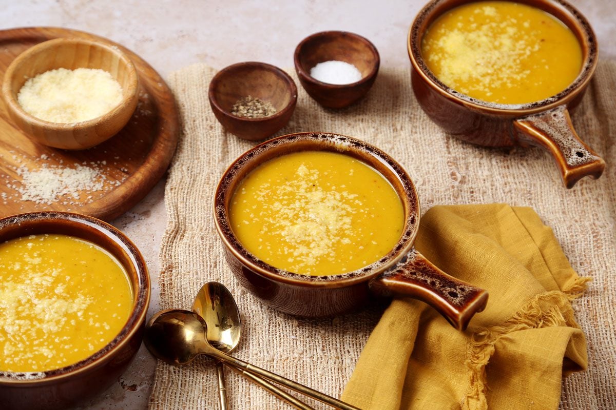 Close up of Taste of Home's butternut squash and sweet potato soup served in brown soup crocks on a brown marble surface.
