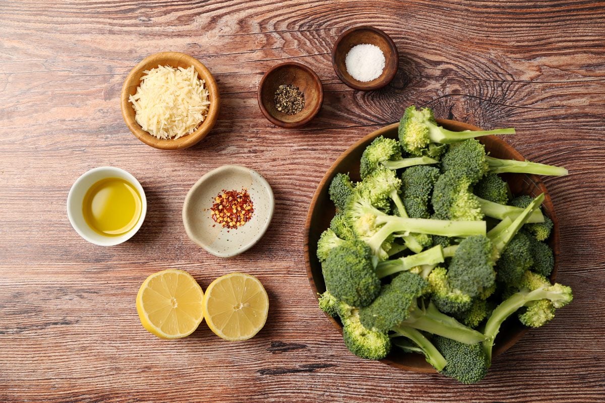 Ingredients for Taste of Home's Grilled Broccoli laid out in small bowls on a brown wooden surface.