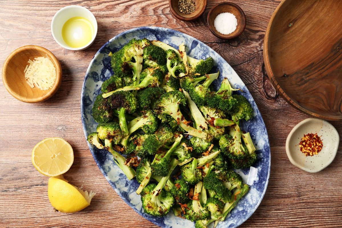 Process of making Taste of Home's Grilled Broccoli grilled and on a plate on a brown wooden surface.