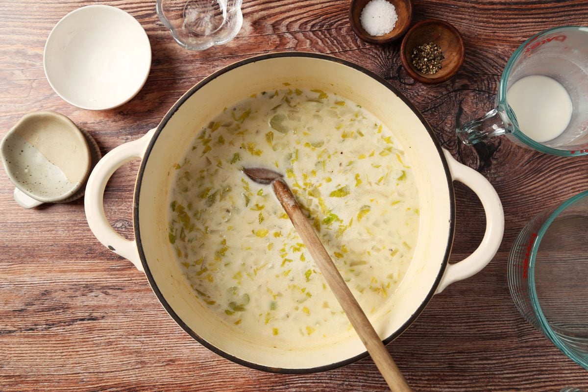 Process of making Taste of Home's Cream of Celery Soup in a large dutch oven on brown wooden surface.