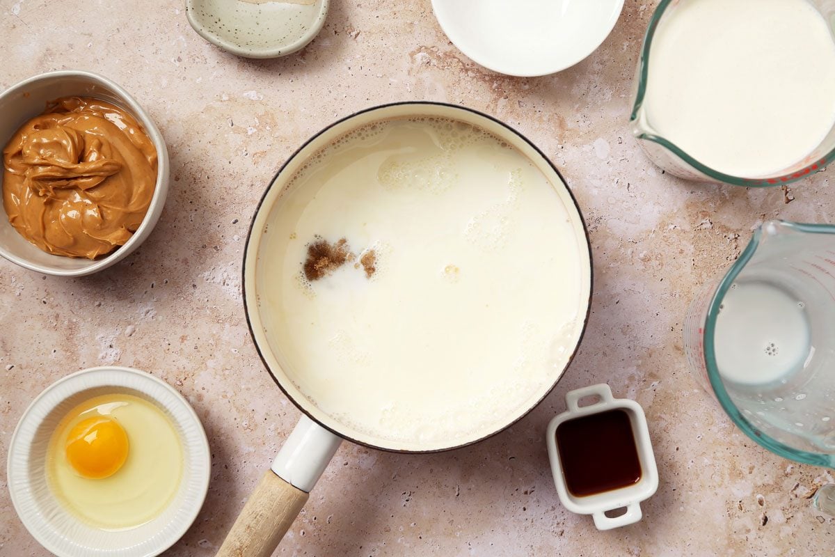 Process of making Taste of Home's Peanut Butter Ice Cream in an ice cream maker on a brown marble surface.