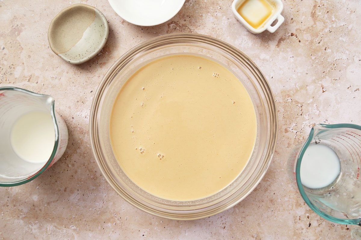 Process of making Taste of Home's Peanut Butter Ice Cream in an ice cream maker on a brown marble surface.