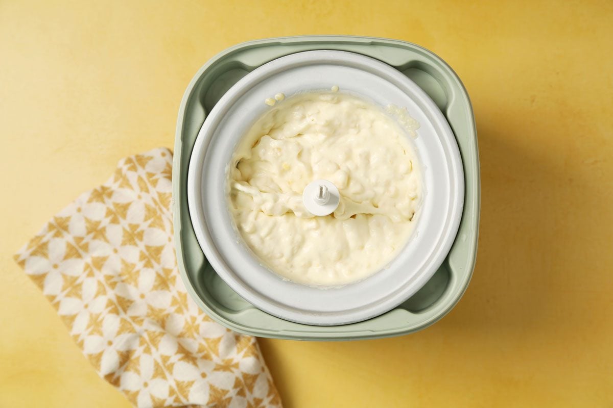 Process of making Taste of Home's Corn Ice Cream in an ice cream maker on a yellow surface.