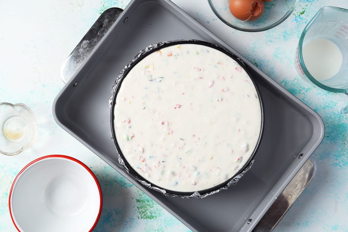 Process of making Taste of Home's Fruity Pebbles Cheesecake cooked in a pan with a water bath.