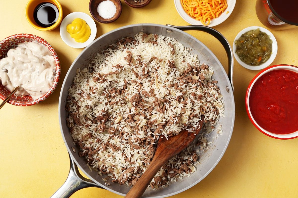 Process of making Taste of Home's Hamburger Casserole in a large nonstick skillet on a bright yellow surface.