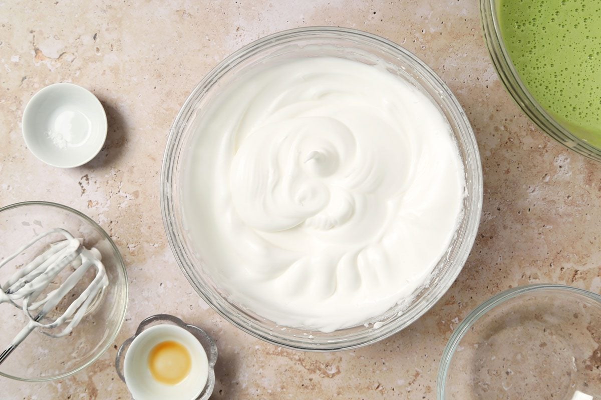 Process of making Taste of Home's Pandan Cake making the cake batter in a large mixing bowl on a brown marble surface.