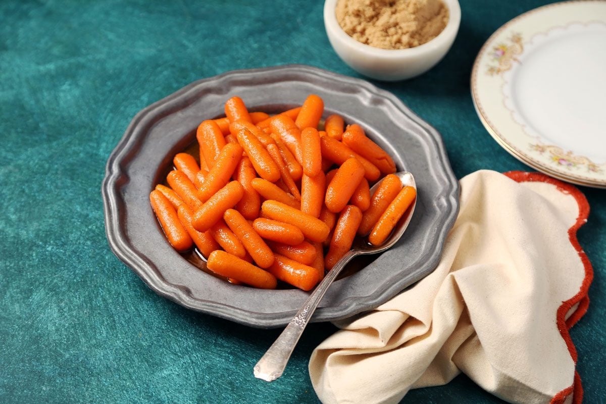 Close up of Taste of Home's Glazed Carrots served on a large dish with a green surface.