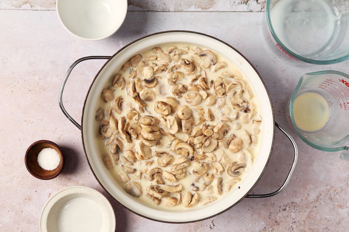 Process of making Taste of Home's Creamed Mushrooms in a large pot on a grey surface.