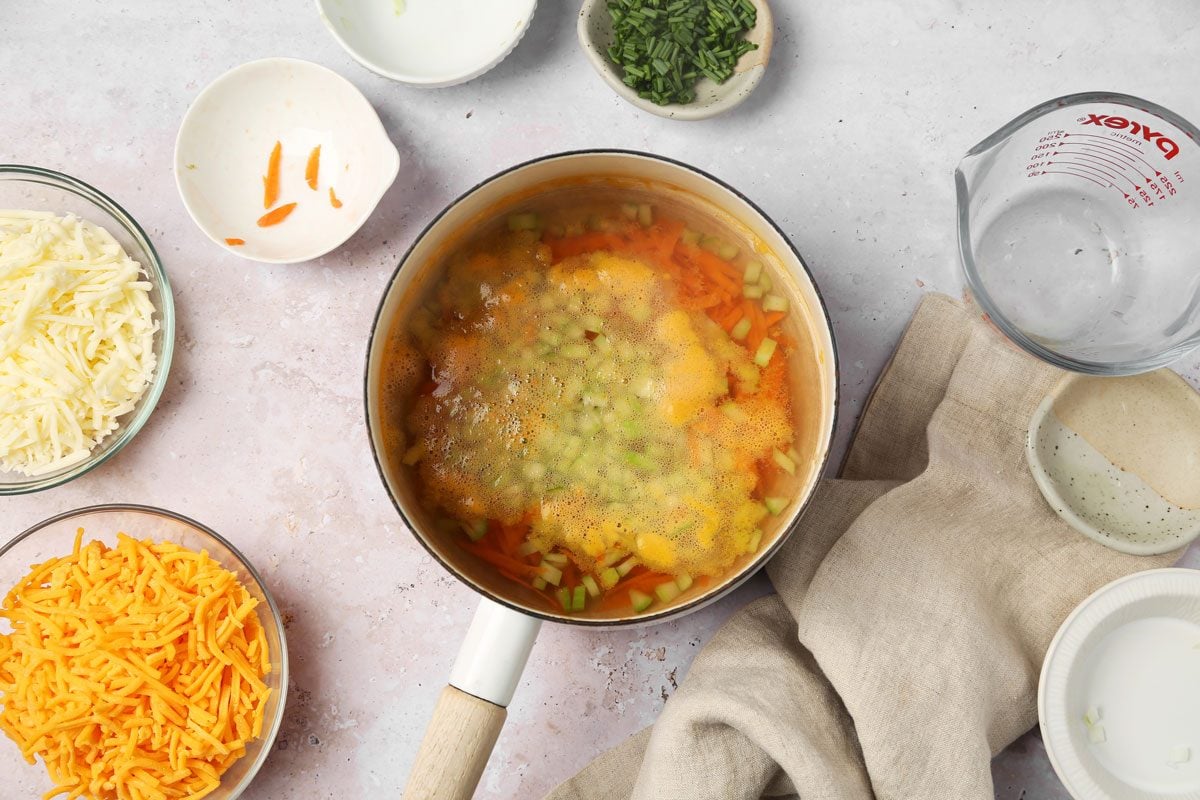 Process of making Taste of Home's Cheddar Cheese Soup in a pot on a grey surface.
