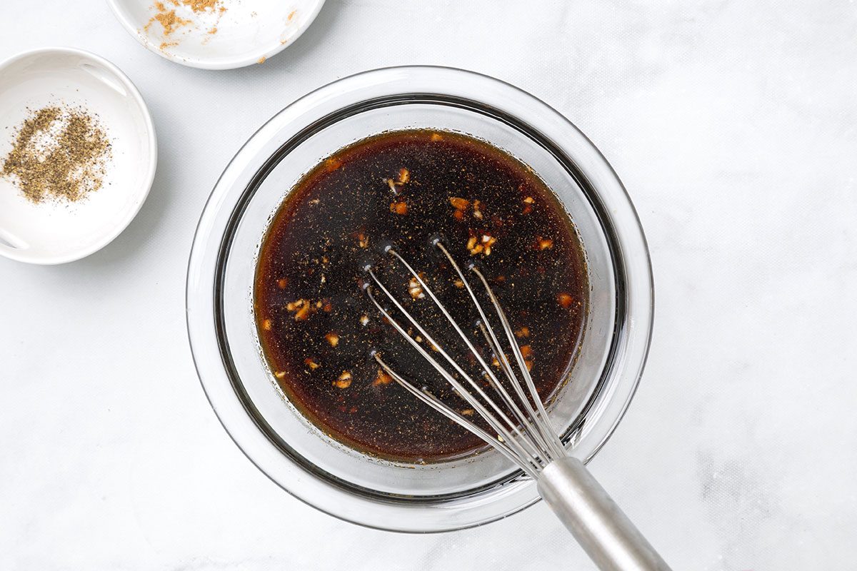 Sugar, soy sauce, vinegar, garlic, ginger and pepper mixed together in a bowl for step one of Teriyaki Chicken Thighs recipe for Taste of Home