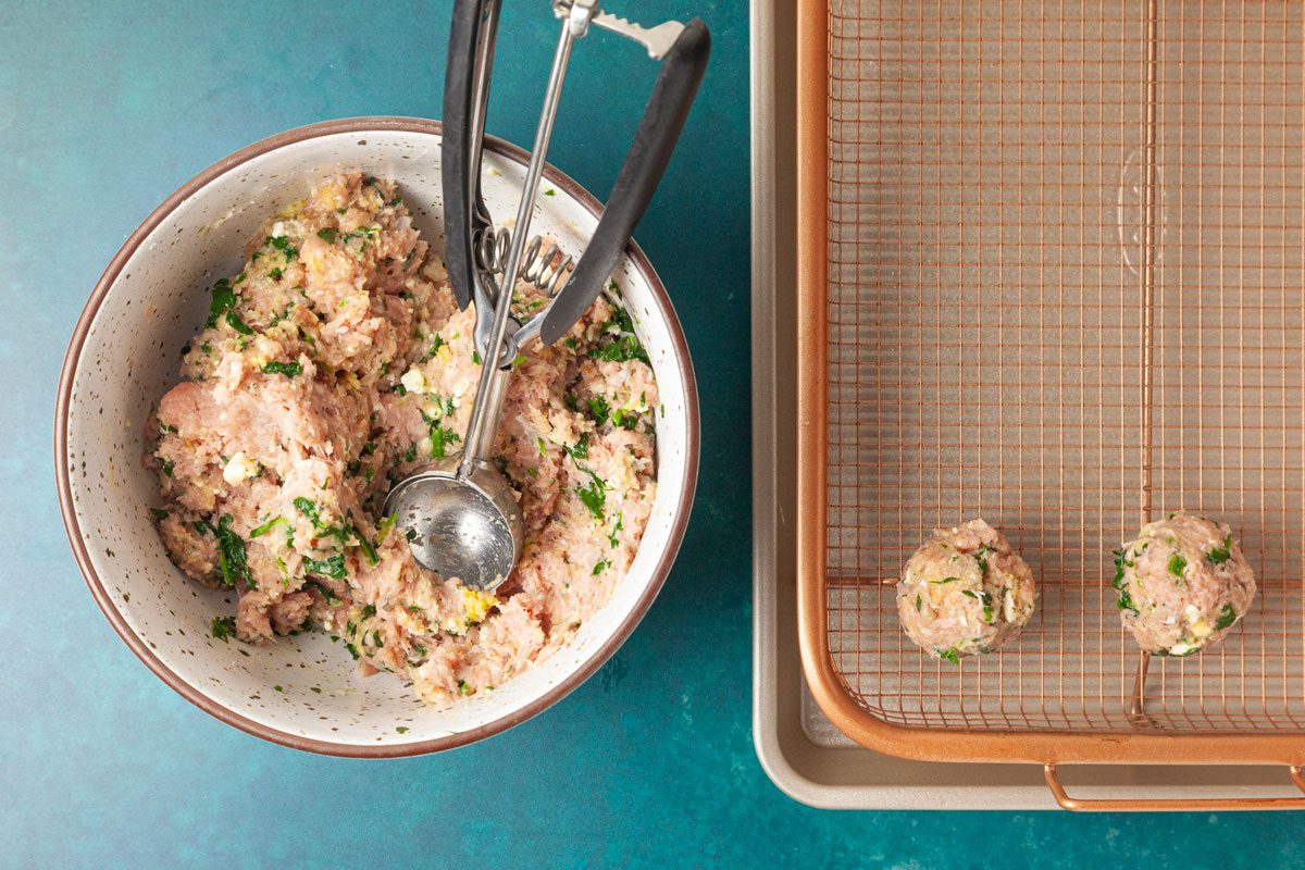 Step 2 of Taste of Home Turkey Feta Meatballs is to combine the ground turkey, feta, bread crumbs, beaten egg, parsley, salt, basil and pepper. Add the spinach mixture and mix everything until just combined. Shape the turkey mixture into 1-1/2 inch meatballs and arrange them an inch apart on a rimmed baking sheet fitted with a greased wire rack.
