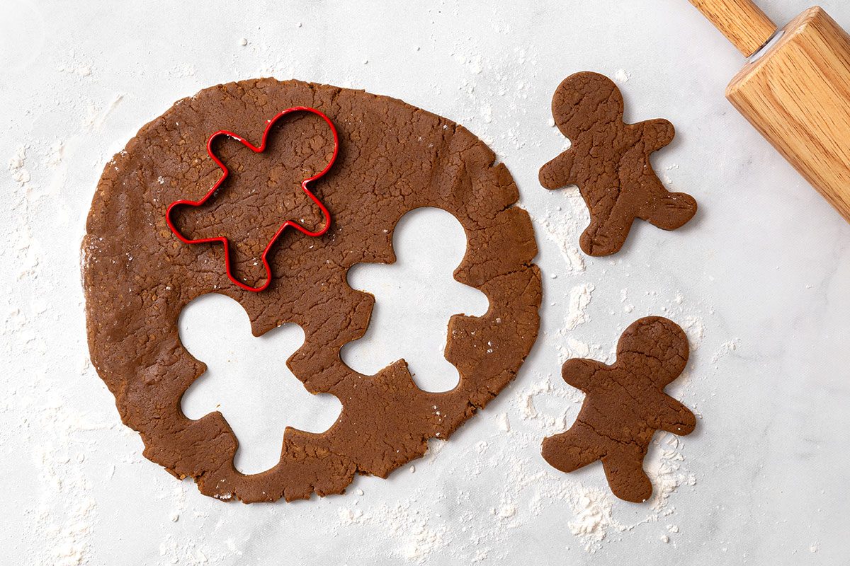 Gingerbread cookie dough rolled out on a floured surface with gingerbread cut outs for step four of Wookie Cookie recipe for Taste of Home