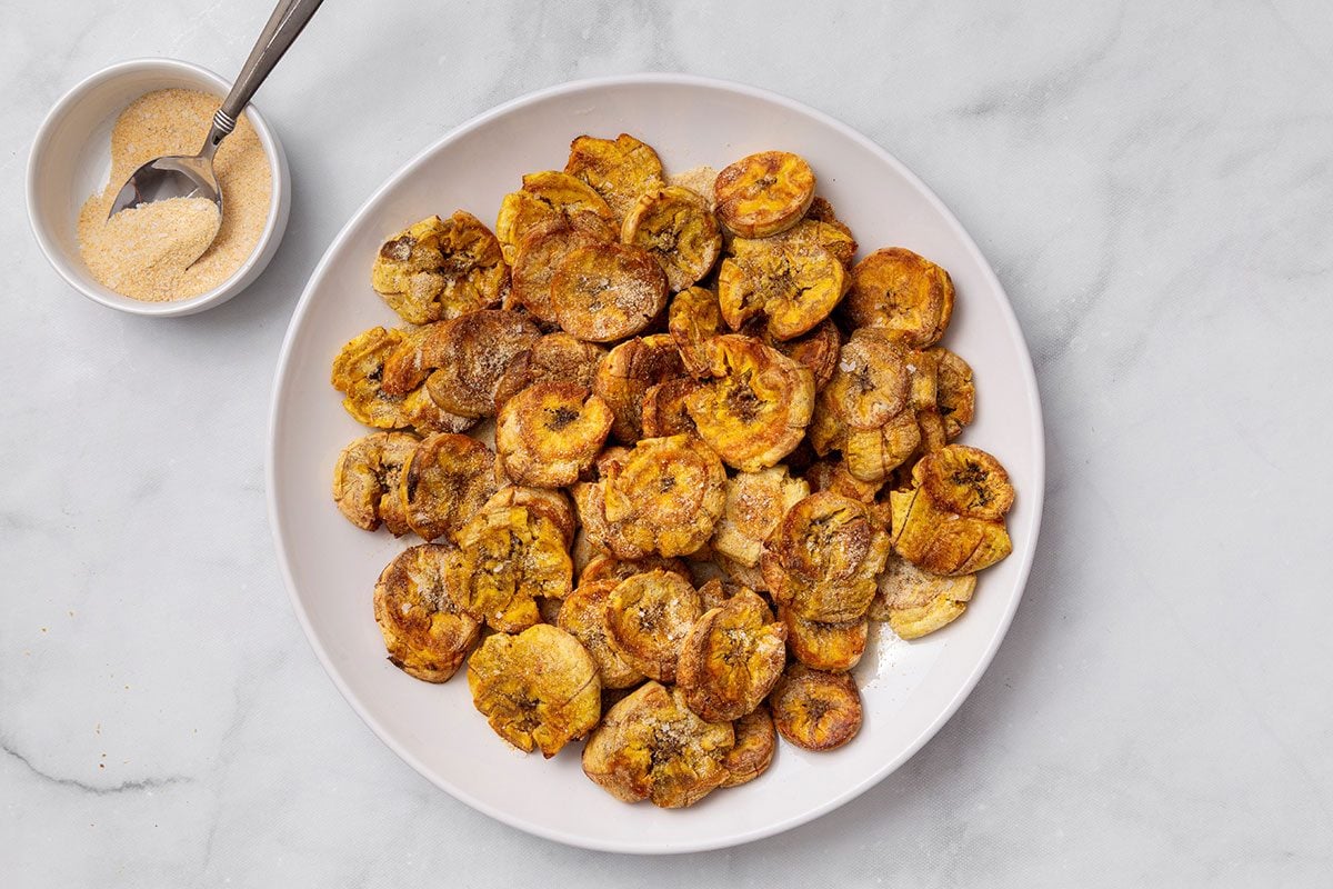 Garlic powder, garlic salt, onion powder and salt seasoning on crispy plantains for step five of Air-Fryer Plantains recipe for Taste of Home