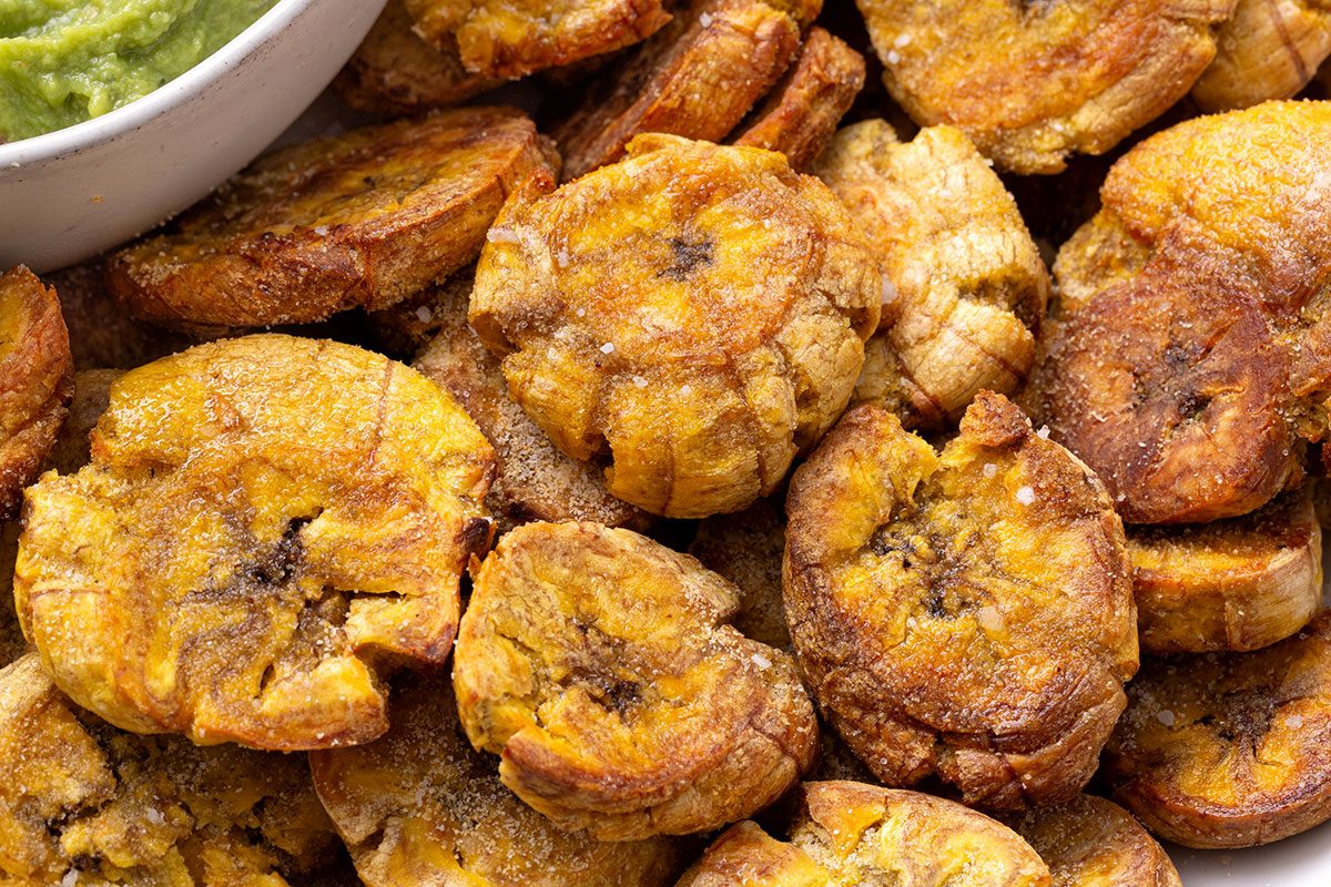 Close up of sliced and seasoned Air-Fryer Plantains on a plate with guacamole dip for Taste of Home