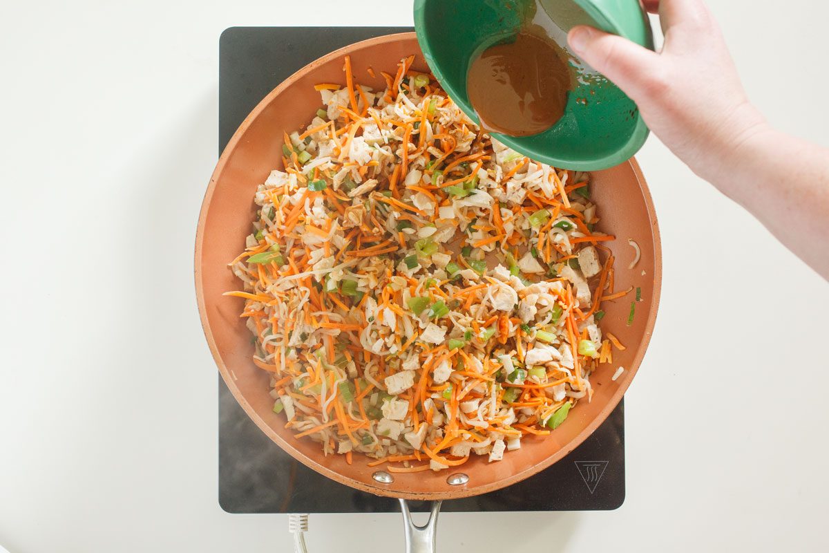 Adding soy sauce to vegetables in skillet