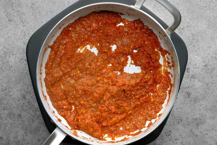 A sauce is being created in the same skillet, where the sautéed onions are blending with other ingredients.