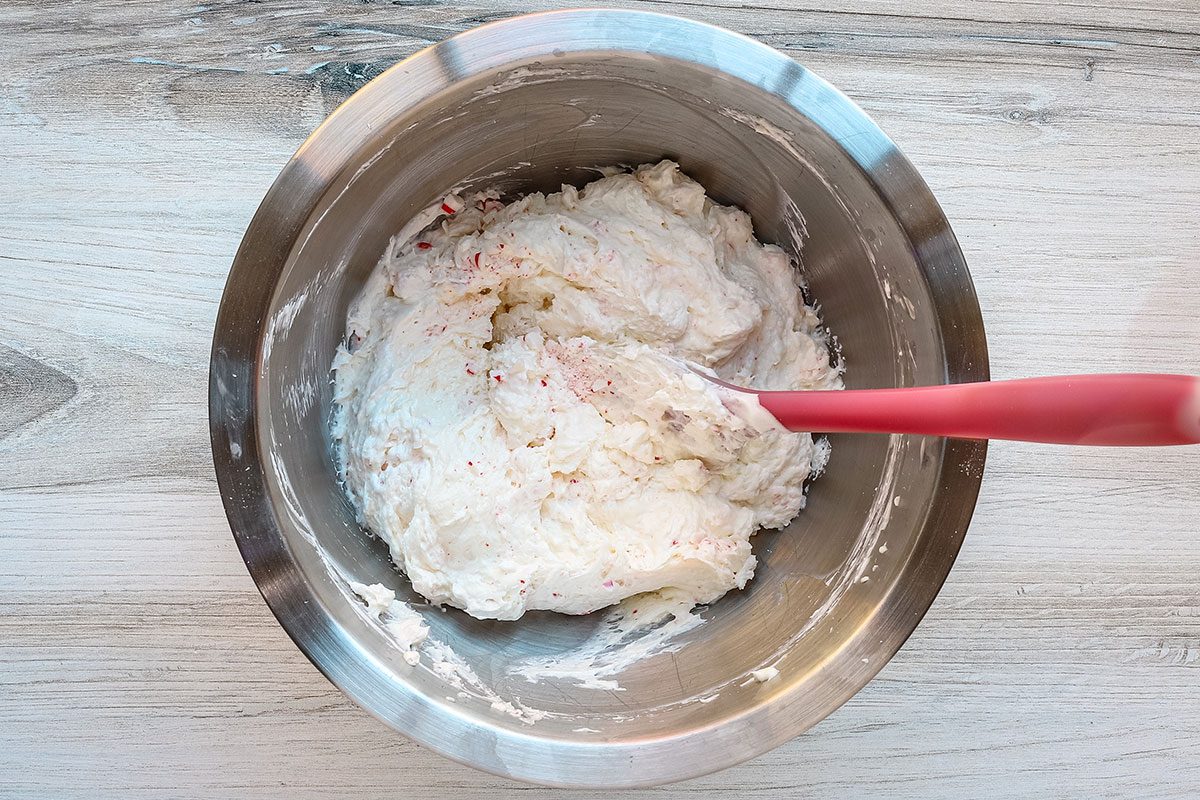 Combining the cream cheese with whipped topping and crushed candy.