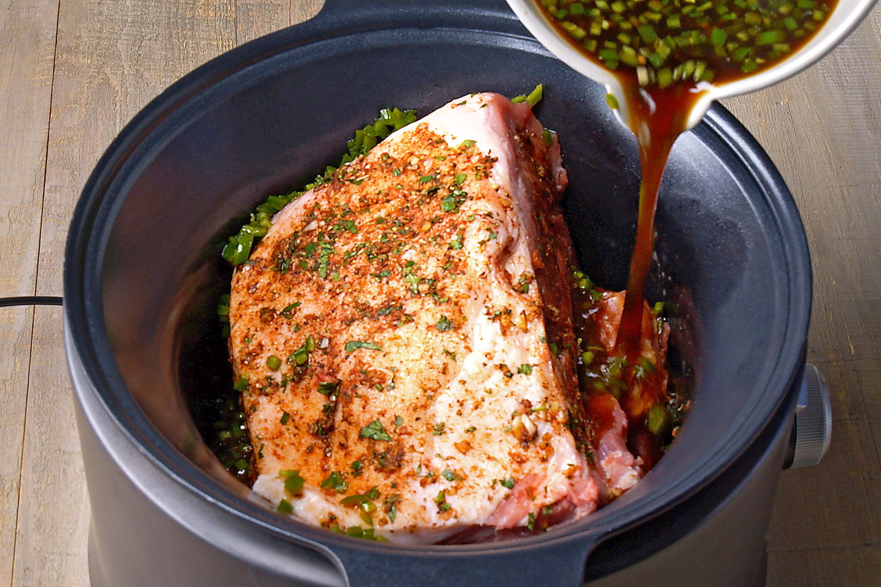 pineapple juice, soy sauce, stock, lime juice and pepper mixture being poured around the meat