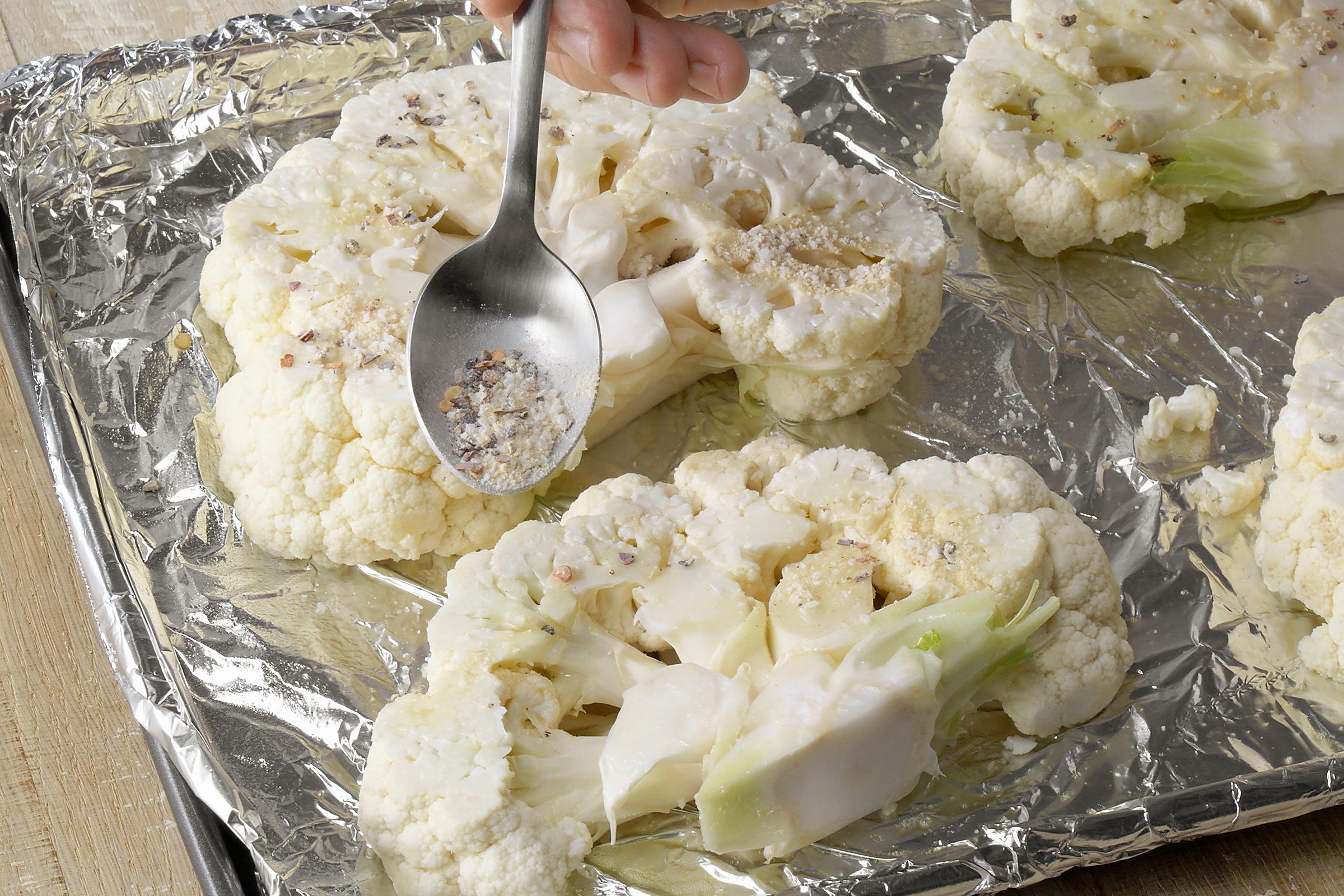Sprinkling seasoning mixture over cauliflower slices