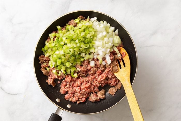 Ground sausage, chopped celery and onion in a large skillet for step two of Cornish Game Hens with Wild Rice Stuffing recipe for Taste of Home
