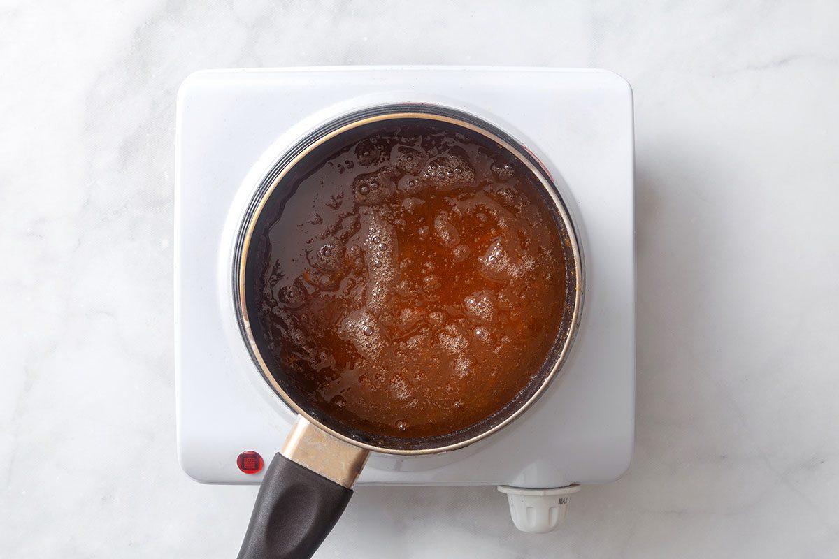 Apricot preserves and half a cup of water boiling in a saucepan for step four of Cornish Game Hens with Wild Rice Stuffing recipe for Taste of Home
