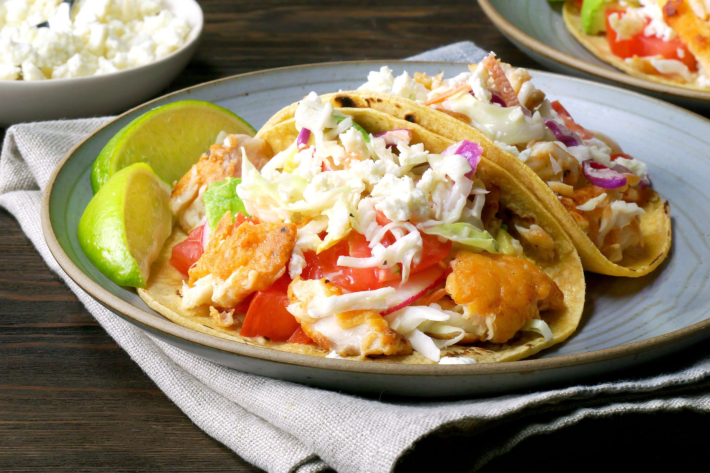 Fish Tacos served in a plate with lemon on side