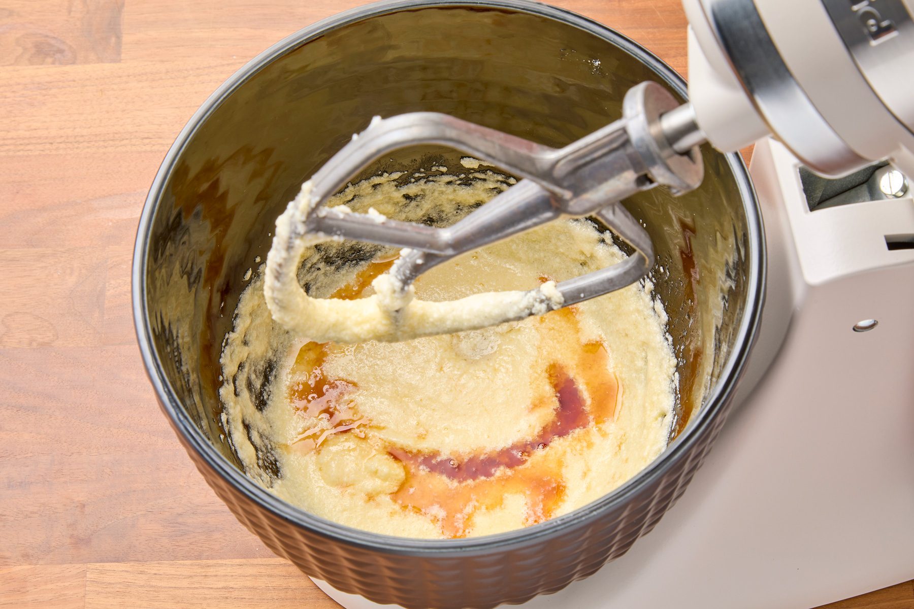 Overhead shot of dark rum and vanilla extract being beaten into a batter until fully combined.