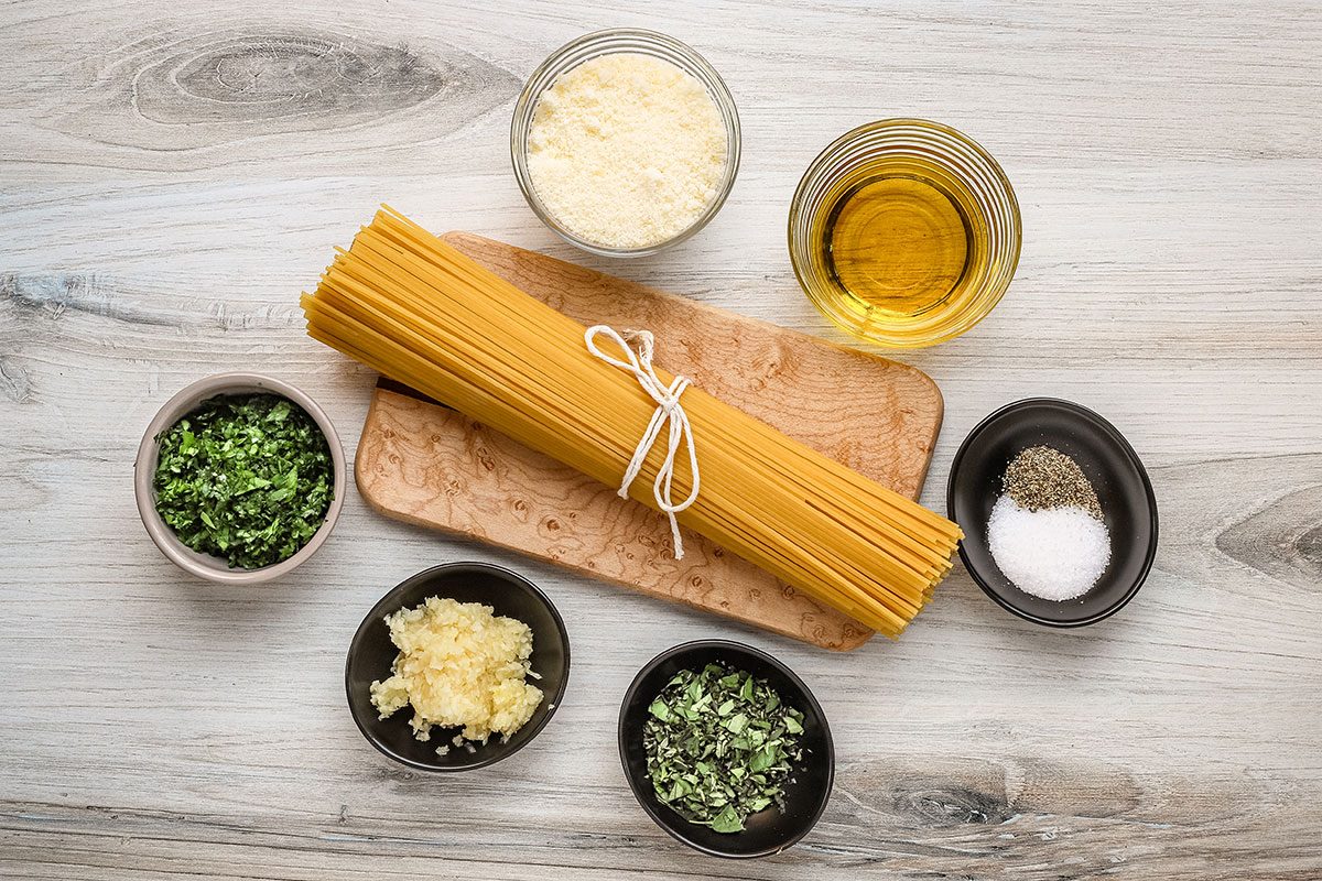 Ingredients for garlic spaghetti, including spaghetti, garlic; olive oil, oregano, parsley, Parmesan cheese and salt and pepper.