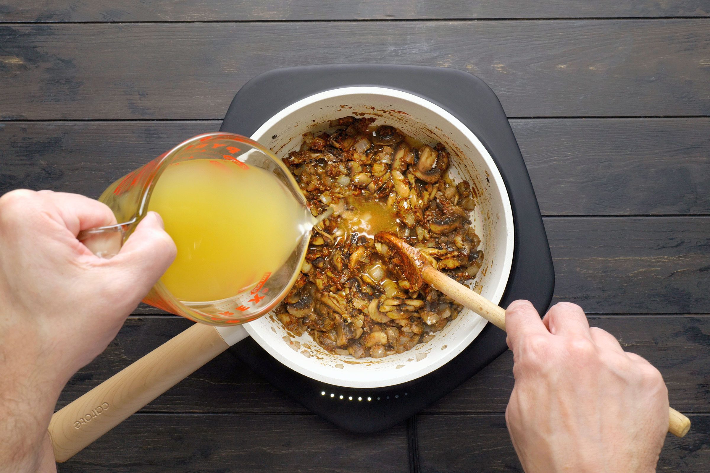 adding broth to the sautéd mushrooms in a pan