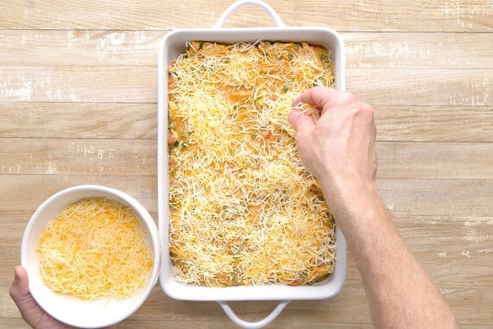 Cheese sprinkled on chicken mixture in a baking dish