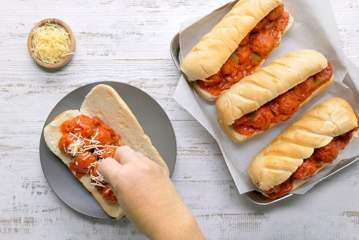 Italian Meatball Subs in a baking pan served on plate sprinkled with shredded cheese