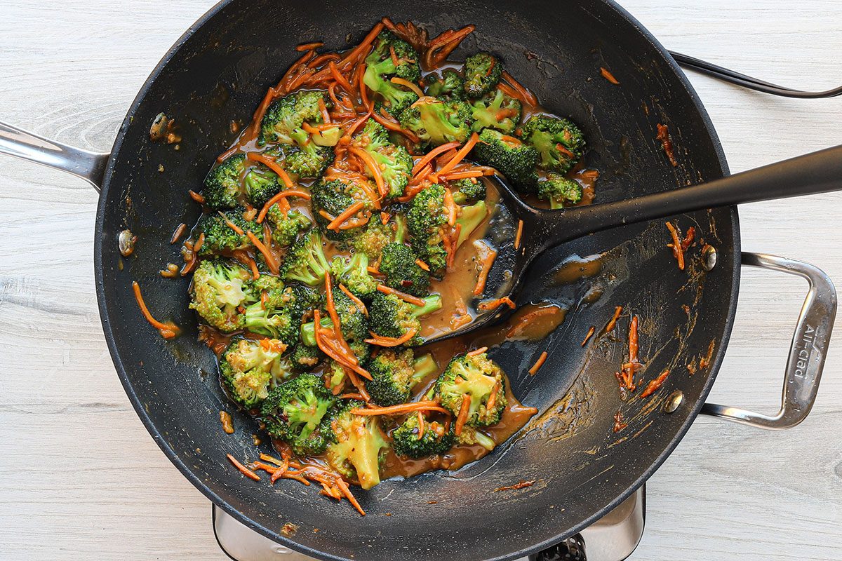 Stir-frying broccoli and carrots for a homemade peanut chicken stir-fry recipe.