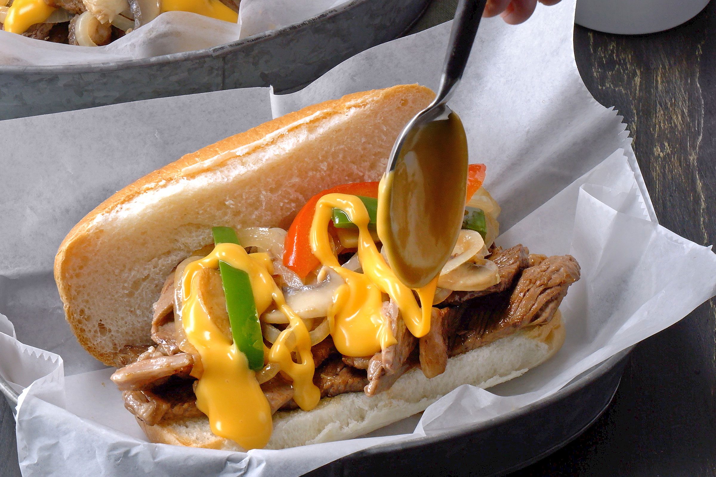 Adding sauces while assembling the philly cheesesteak