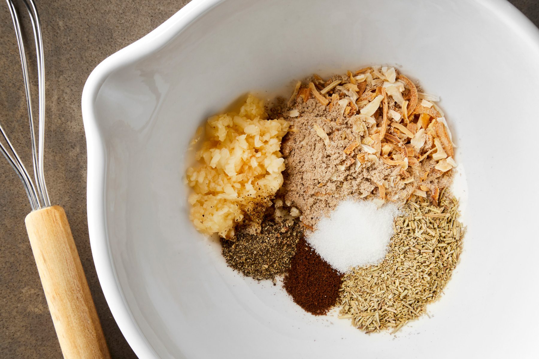 overhead shot of a large bowl combined the first six ingredients, wooden whisker placed near the bowl;