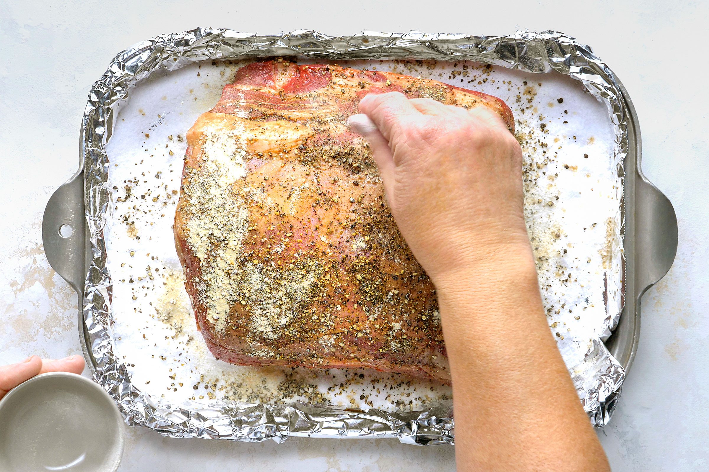 Sprinkling roast rib with garlic powder and grounded black pepper.
